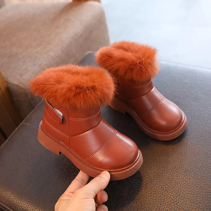 Schwarze und weiße Winterstiefel für Kinder von Hand gehalten.
